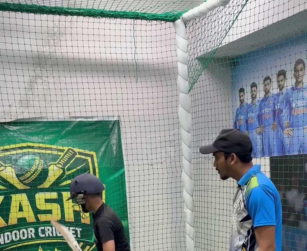 A player receiving instruction during indoor batting practice
