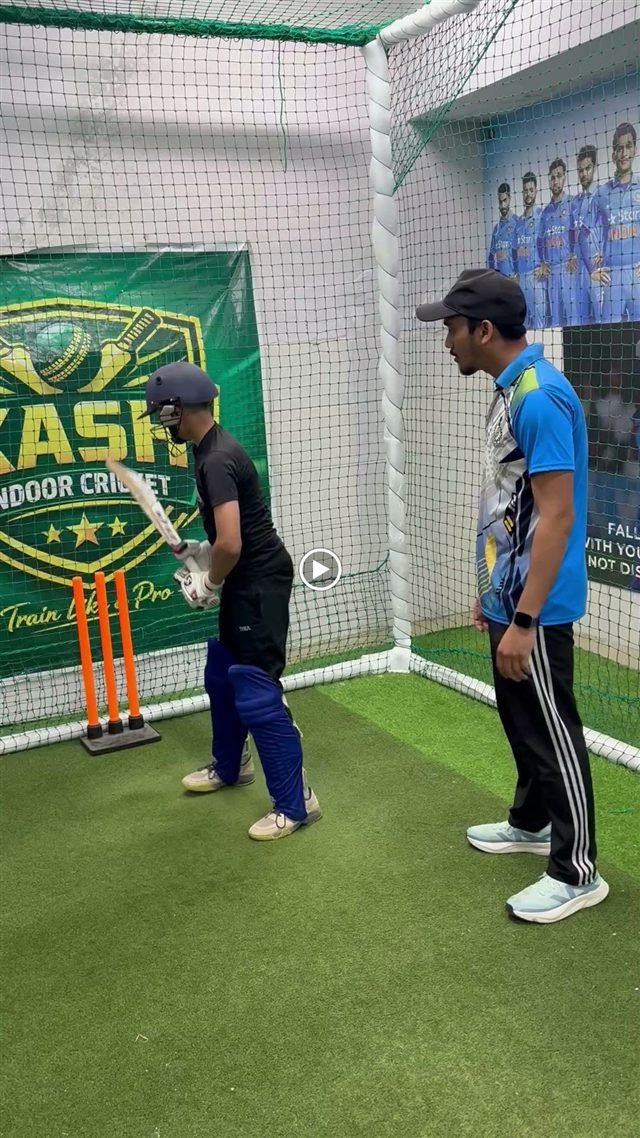 A video still of a player and coach during batting practice.